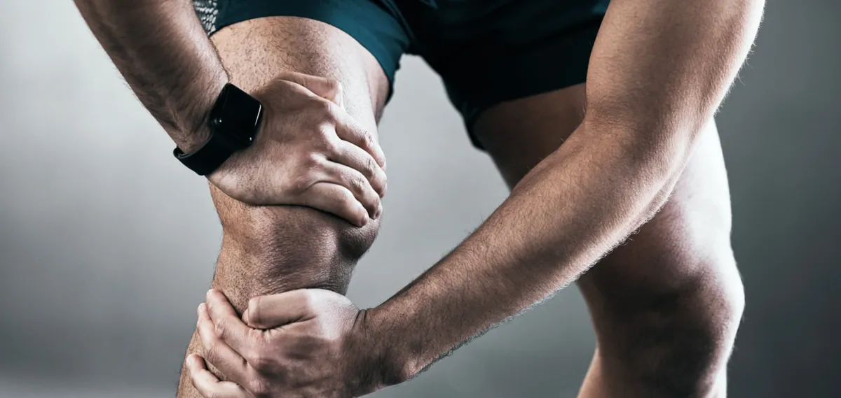 Sportif tenant son genou douloureux en lien avec une tendinopathie rotulienne